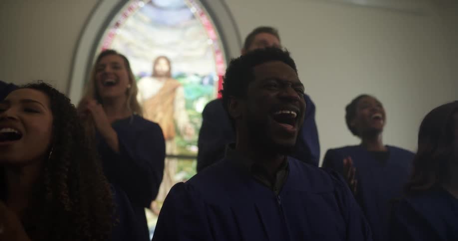 Black and white churchgoers sing and clap in a choir
