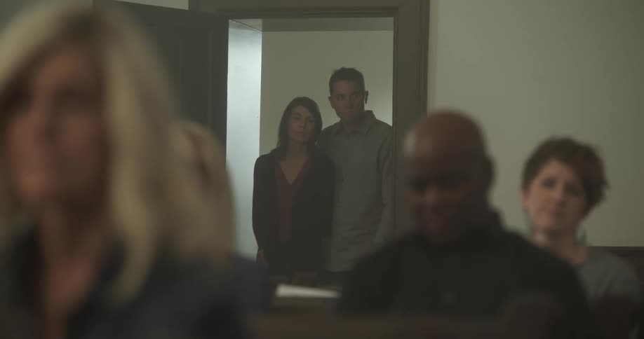 Couple enters to church and walk inside to sit on a pew