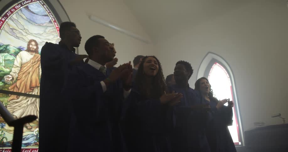 A choir group sings and claps in a church