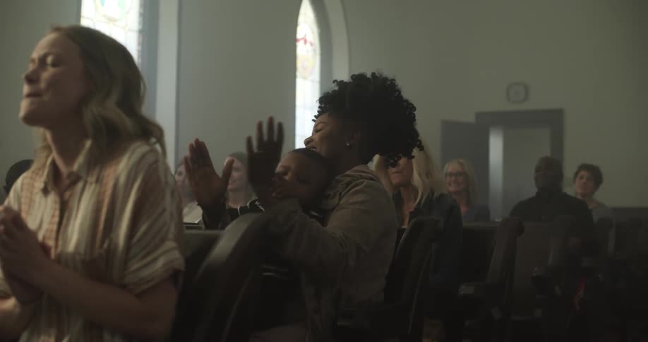 People singing and clapping hands while sitting on pews in a church