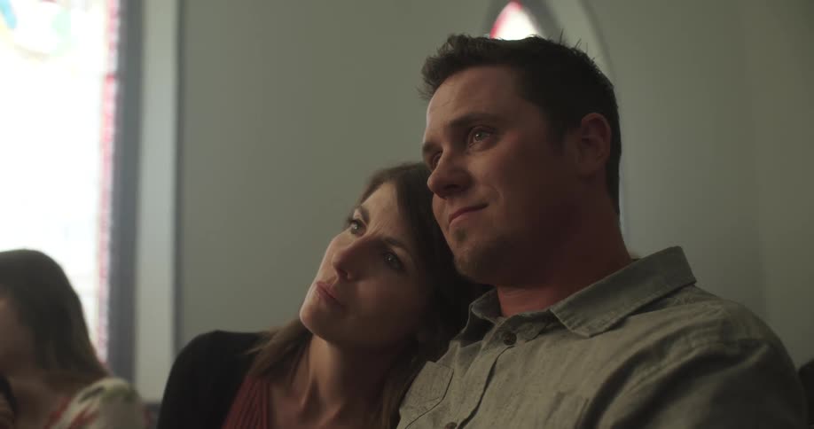 A man and woman lean on one another while sitting in church