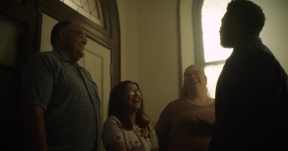 Four people stand inside a room and talk and laugh together