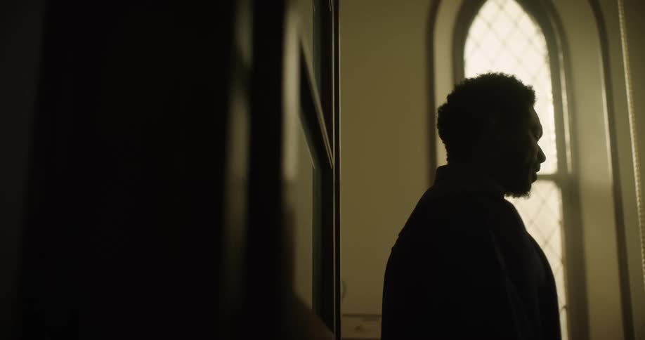 A black man stands in a church and talks