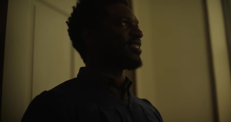 A black man stands in a church and talks and smiles