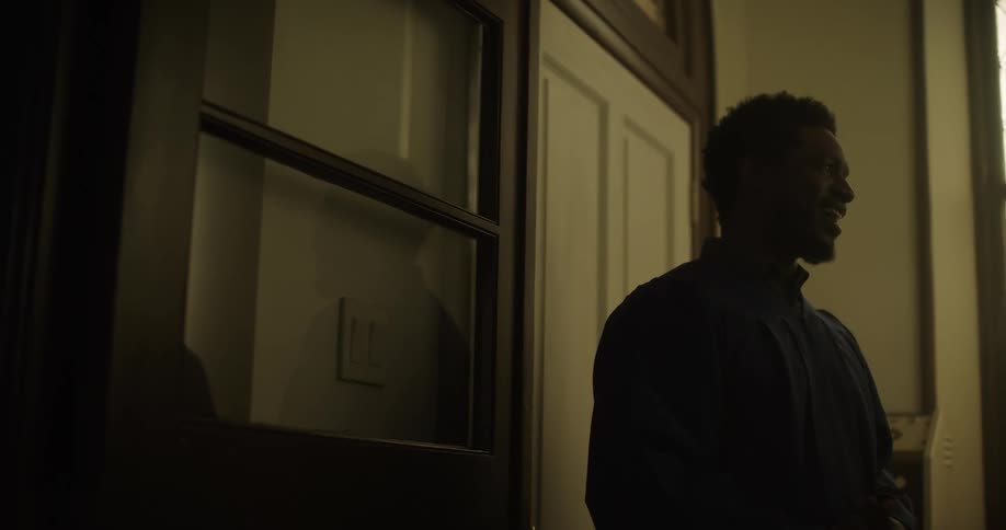Black man having a conversation while standing near a door indoors