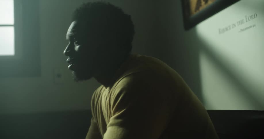 A black man sits down on a couch in a church
