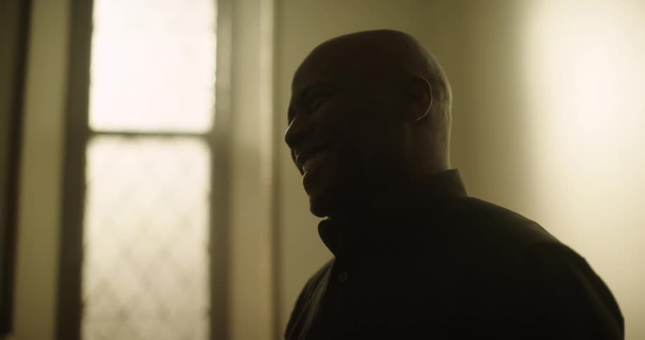 Two black men in silhouette talk and smile and nod