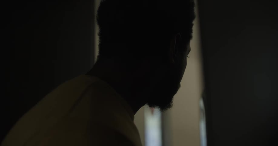 A man peers through a doorway in to a room and then backs away
