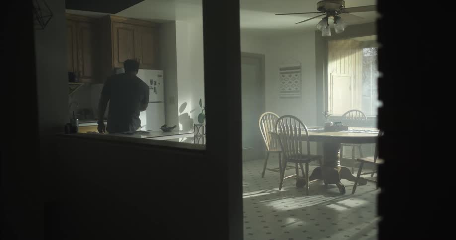A black man stands in his kitchen and opens the refrigerator door
