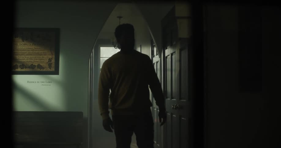 A man walks down a dark hallway in a home