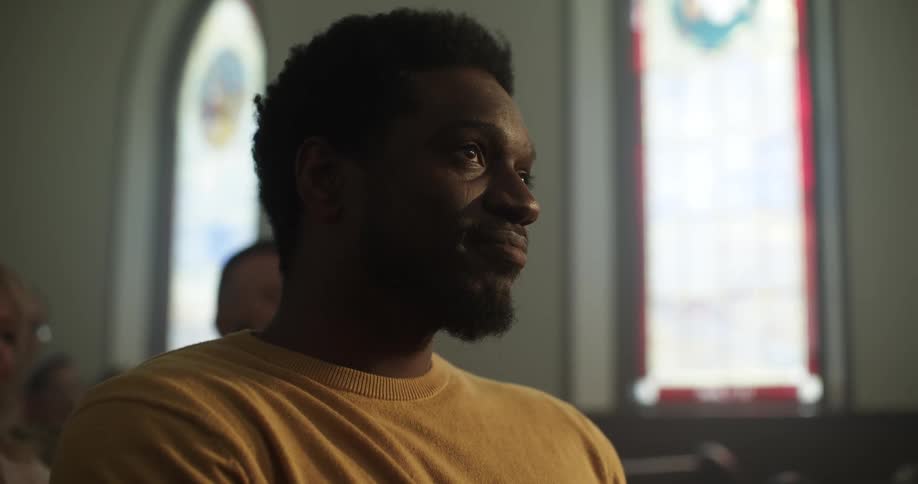 A black man sits in church and enjoys the service with other parishioners