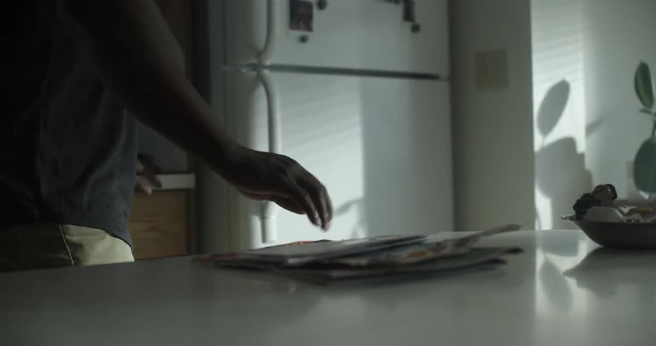 A black man goes through his mail and then opens the refrigerator