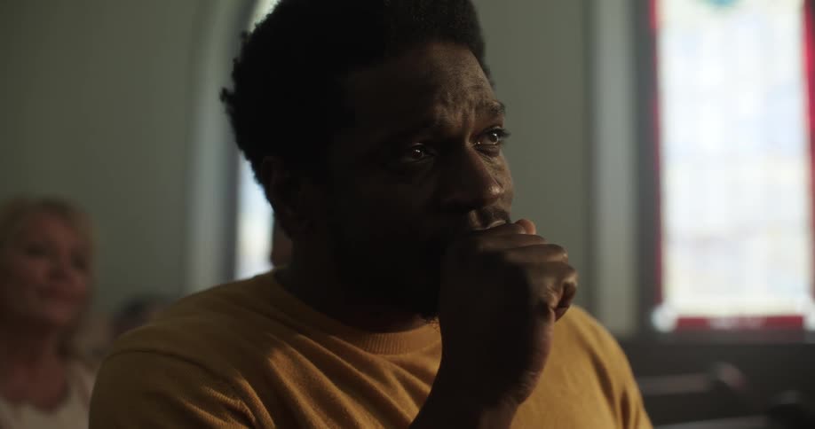 A black man tears up while sitting in a church