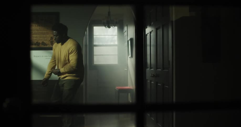 A black man walks in to a room and sits down