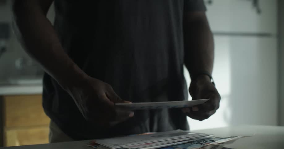 A man sets a pile of mail down and looks through it