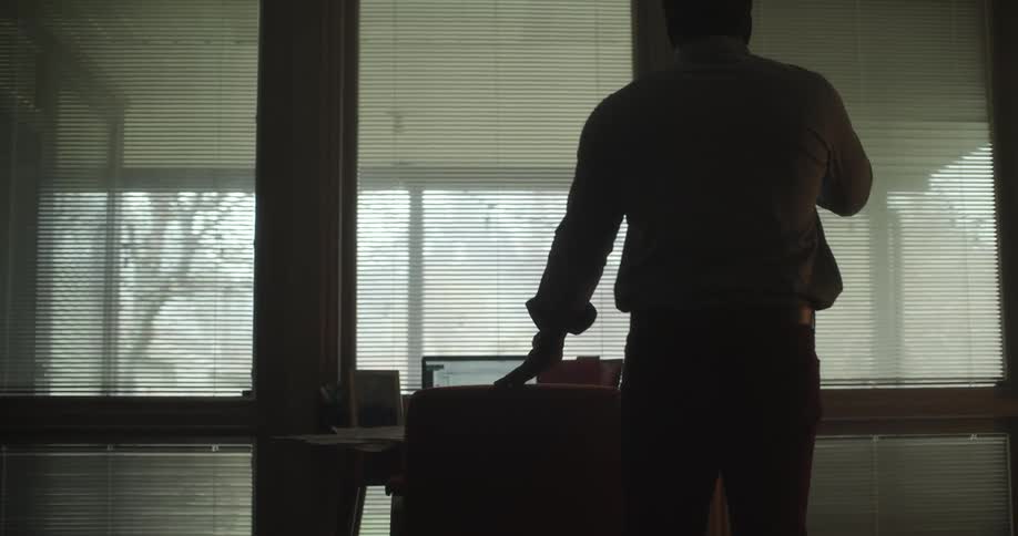 A walks to his office desk with a glass of water and sits down