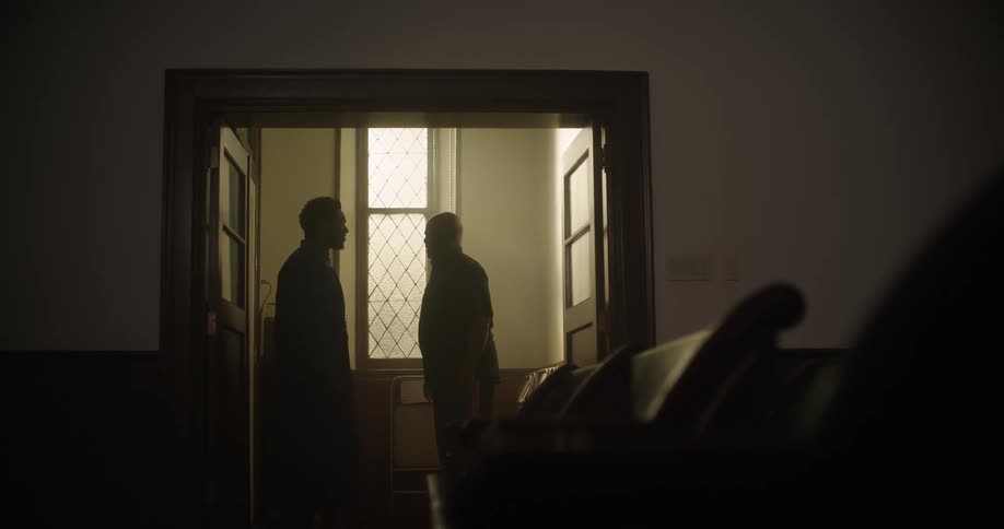Two men talk in a small room in a church
