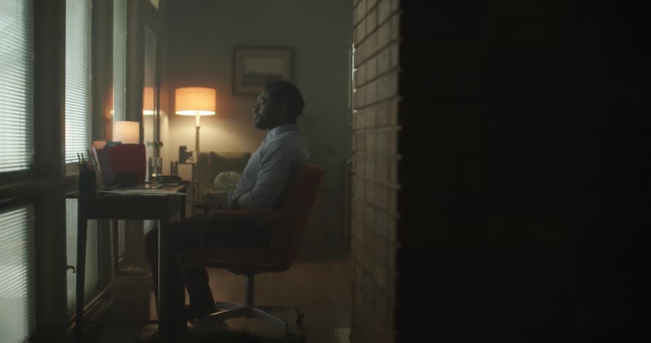 A man sits at a desk and uses his laptop