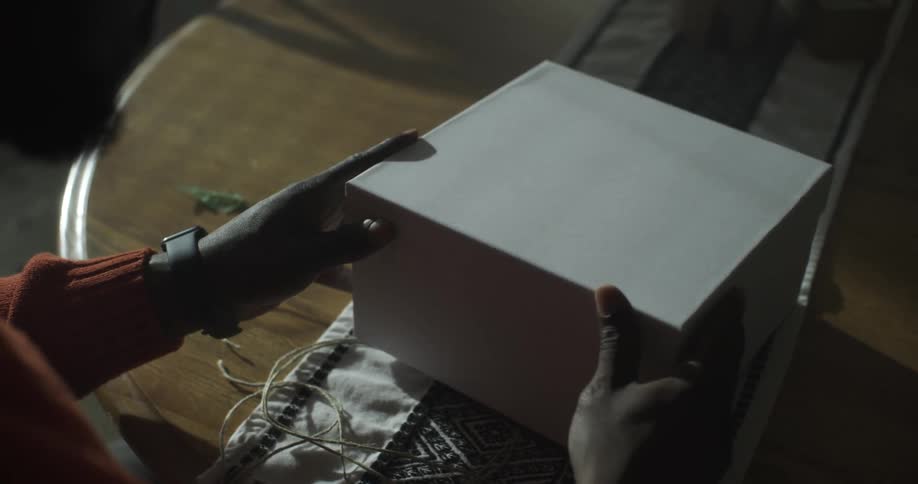 A man opens a gift box to reveal a card and tissue paper