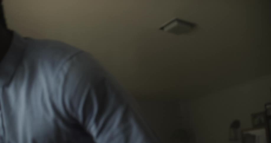 A man drinks a glass of water as he walks across a room