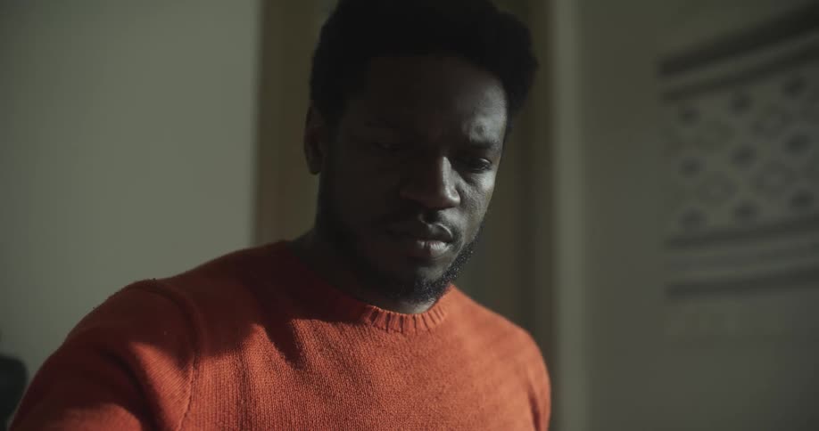 A black man reads a slip of paper and sorts through other papers