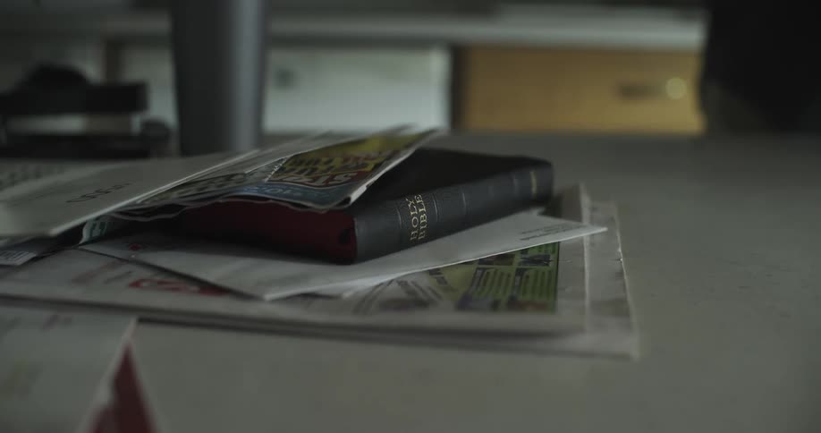 Person drops letters on a bible over the table