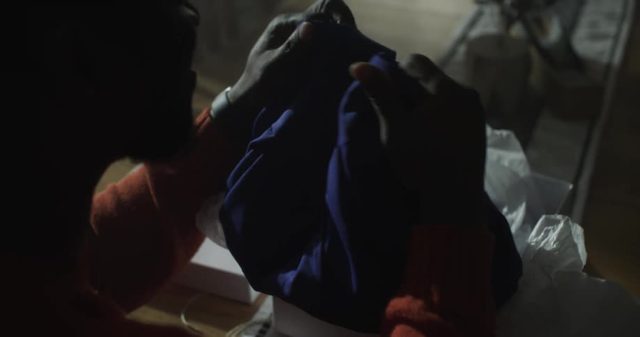 A black man looks at a blue robe and claps his hands together