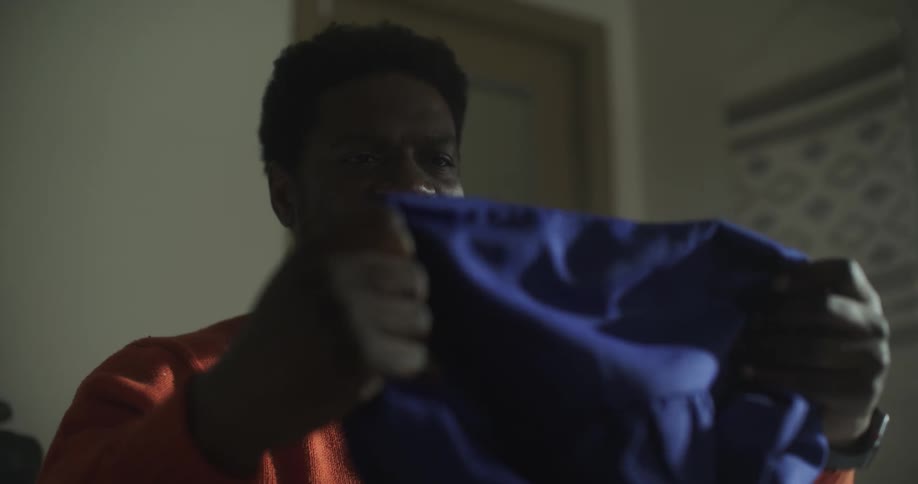 Black man pulling out shirt from bag then smiling with happiness