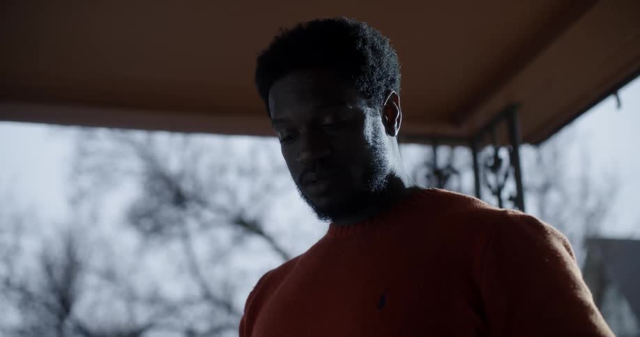A black man looks around outside and walks away