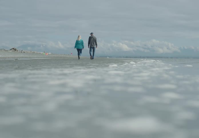 A man and woman walk along the coast line