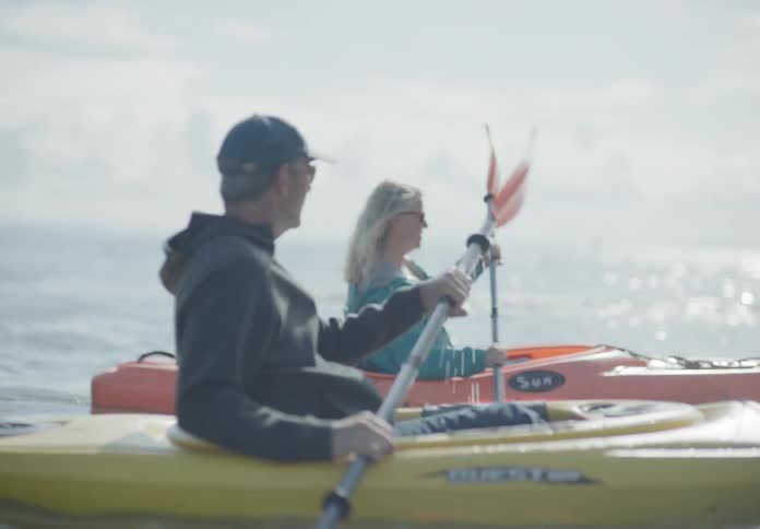 A man and a woman in a lake kayaking