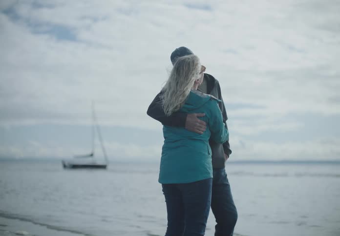 A couple stand on the beach hugging and kissing