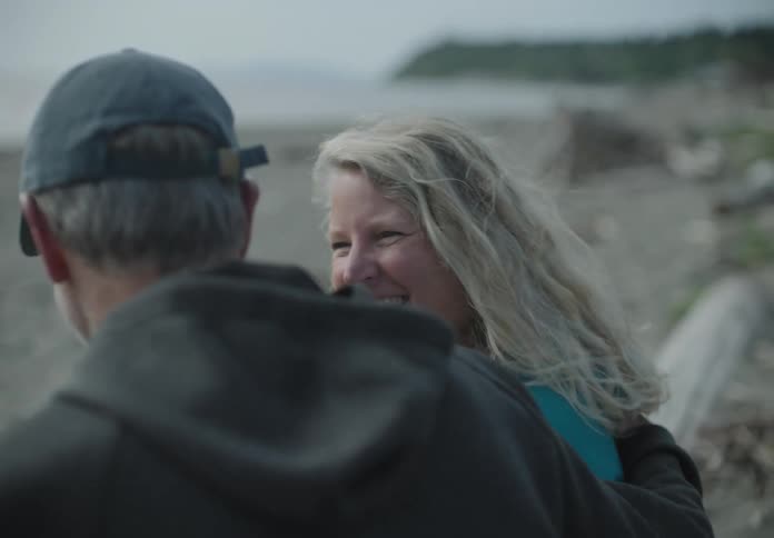 A man and woman talk together standing on the sandy beach