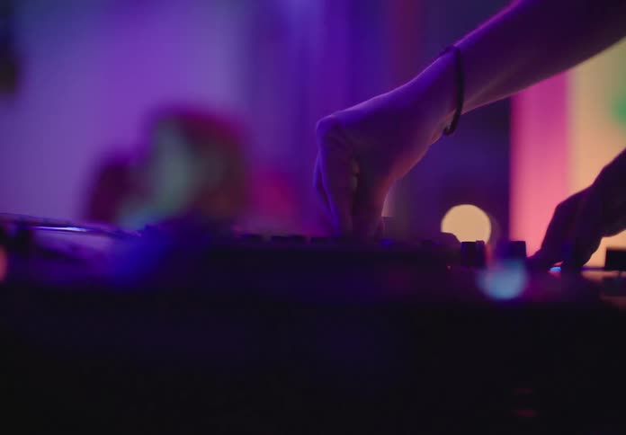 A white male turns dials to provide music for a night club