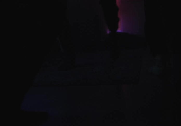 People dancing in their stocking feet at a house party with colorful lights flashing