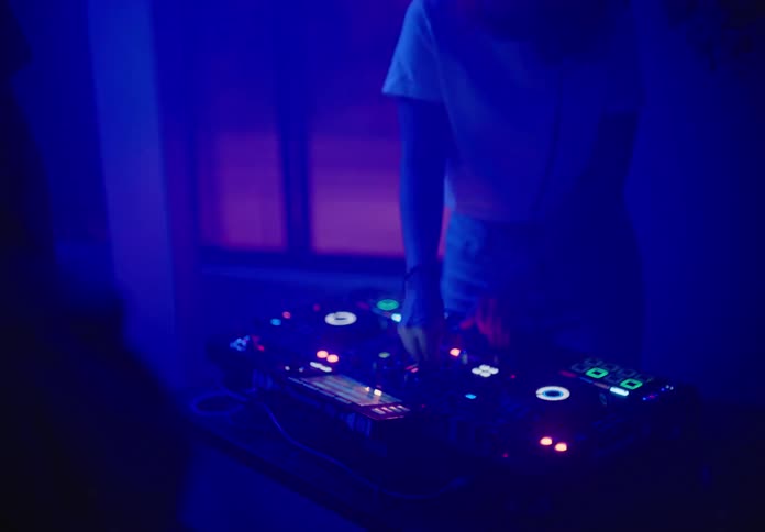A woman djing in a party as people dance