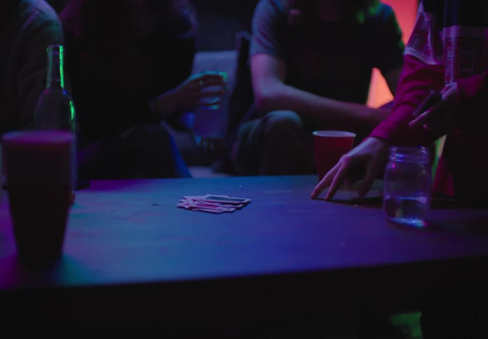 A group of people gather at a club to play cards and drink alcohol