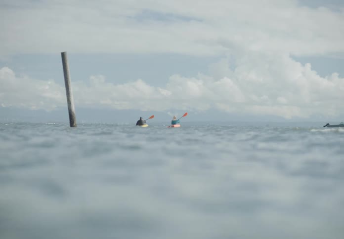 Two people kayak out in the ocean