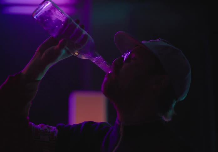 A man chugs a bottle of alcohol at a bar