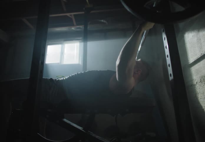 A man bench pressing weights in a basement