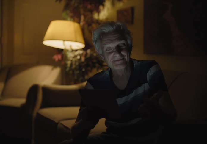A man is sitting on a couch and talking on a cell phone