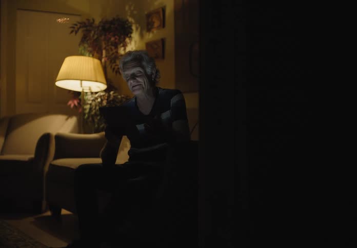 A woman sitting down on a couch video chatting on a smart phone