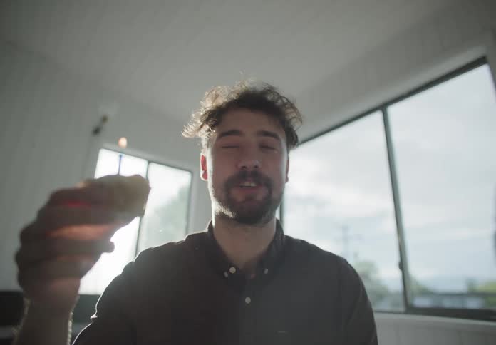 A man with a party hat holding a cupcake with a candle in it