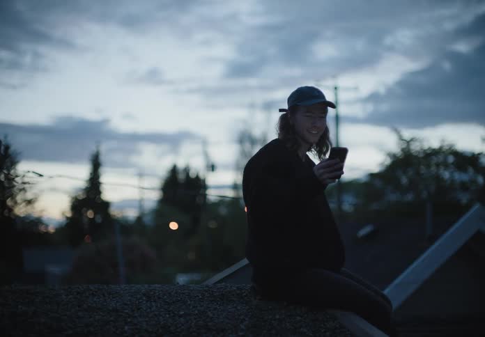 A man sits outside and has a video call on his cell phone