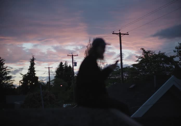 A person is sitting on their roof at sunset