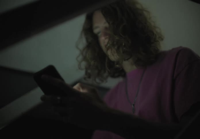 A man sitting down on a staircase looking at a smart phone