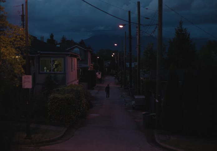A pedestrian is walking in a neighborhood at night