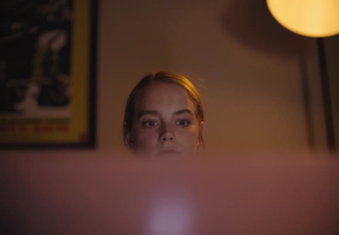 A white woman sits in a room blinking her eyes