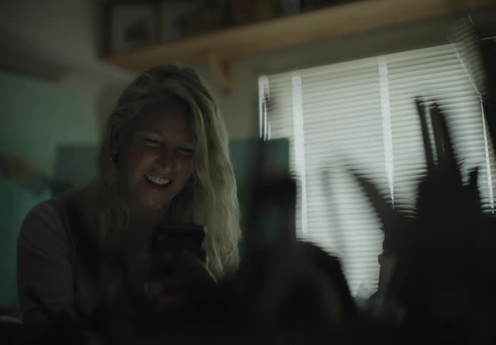 A woman sitting video chatting on a smart phone