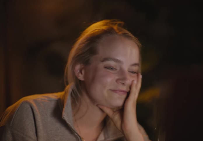 A white woman sits and rocks back and forth and then bursts out laughing at something shes looking at